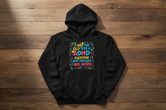 Black ADHD graphic hoodie laid flat on a wooden surface showing full front design