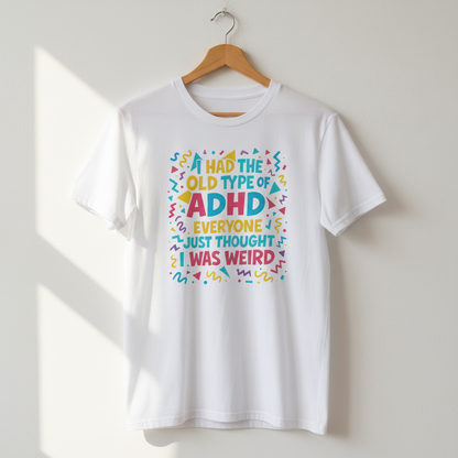 White ADHD graphic t-shirt hanging on a wooden hanger against a light wall with natural sunlight