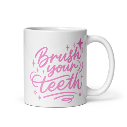 White ceramic mug with pink text reading 'Brush your teeth' with decorative stars and swirls, handle on right side