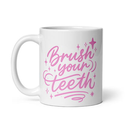 White ceramic mug with pink text reading 'Brush your teeth' with decorative stars and swirls