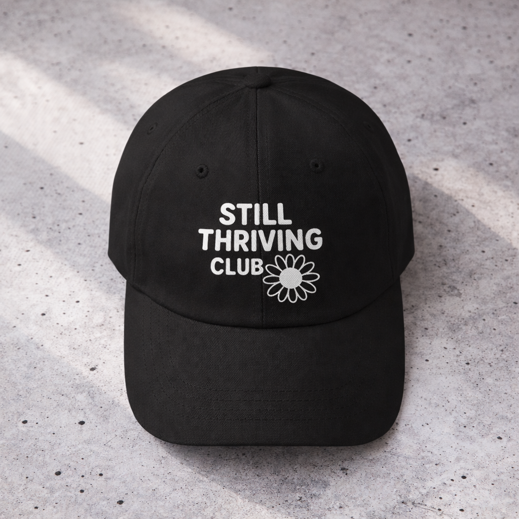 Top-down view of a black Still Thriving Club baseball cap showing the curved brim and white embroidered logo centered on the front panel.
