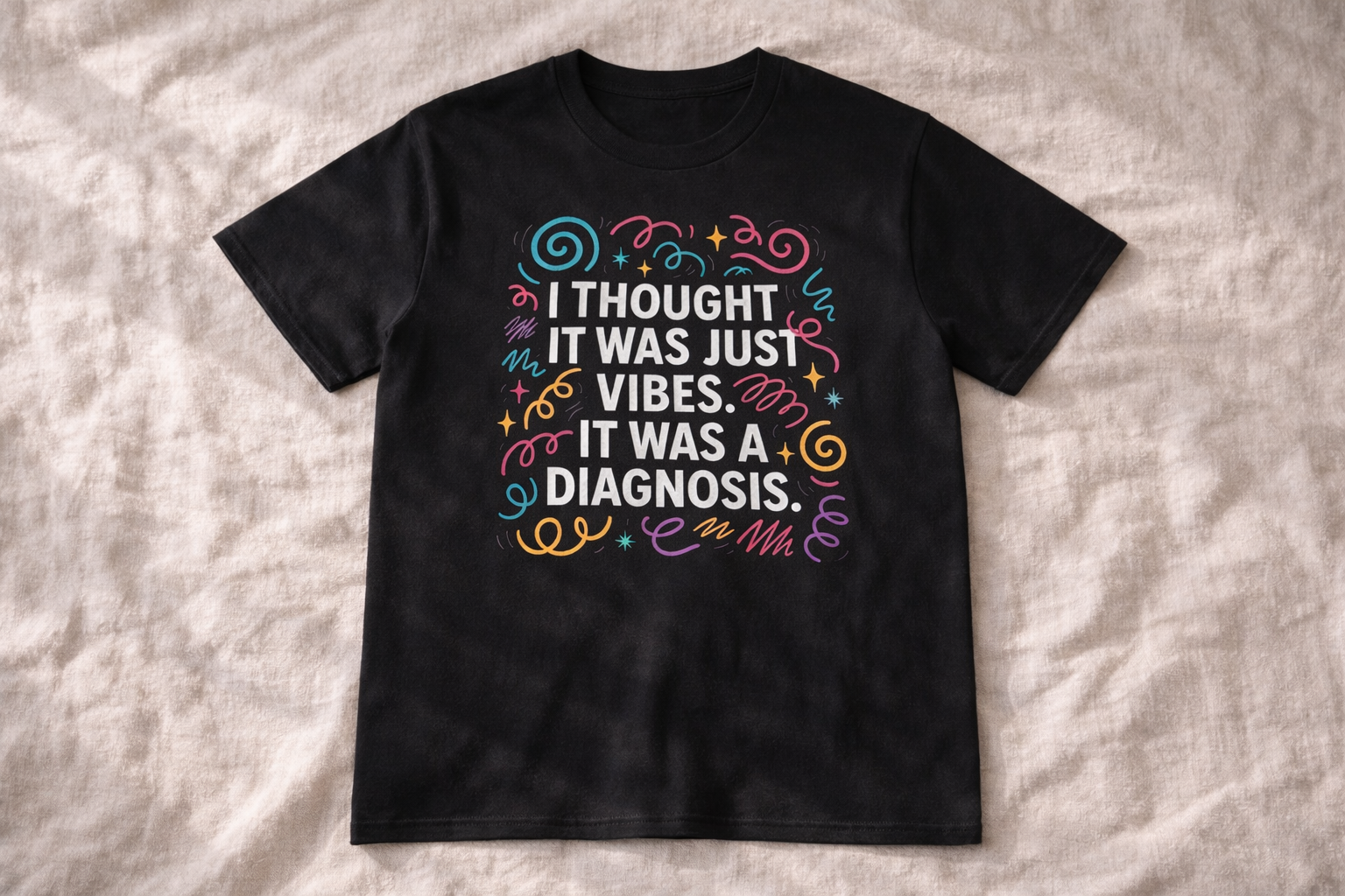Black unisex T-shirt laid flat on a light textured surface, displaying the full colourful mental health–themed design with bold white text.