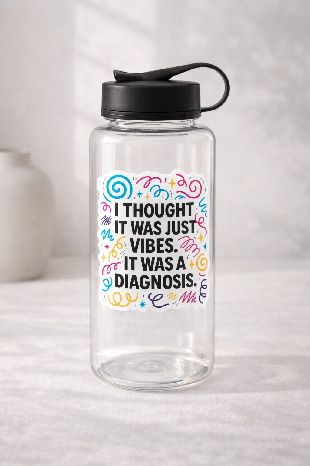 Clear water bottle with a colourful vinyl sticker reading “I thought it was just vibes. It was a diagnosis”