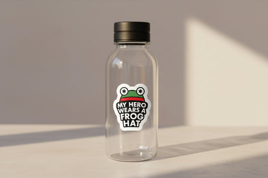Clear reusable water bottle on a light surface, featuring a ‘My Hero Wears a Frog Hat’ vinyl sticker on the front.