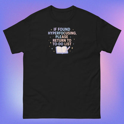 White and purple text reading 'If found hyperfocusing, please return to to-do list' with open notebook and pencil surrounded by stars on black tshirt